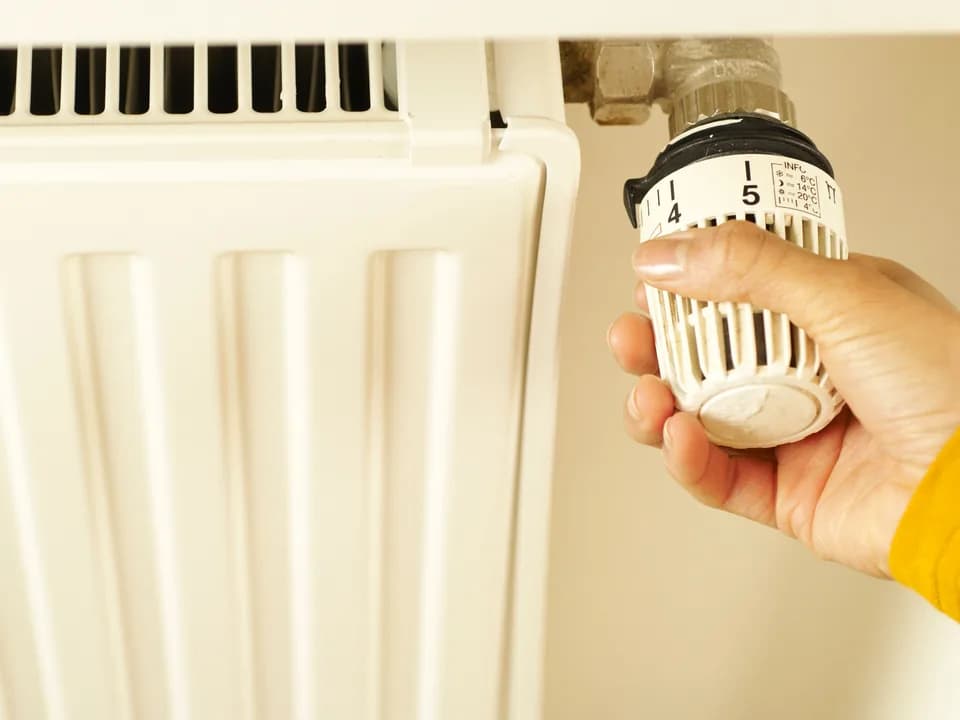 El, radyatör termostatını çevirerek ısıyı ayarlıyor